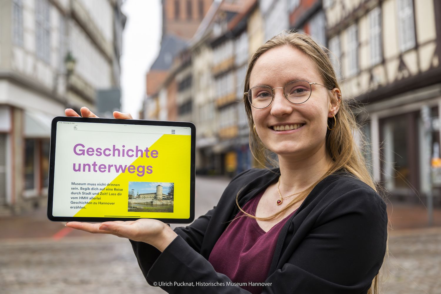 Frau hält Tablet mit Geschichte unterwegs app
