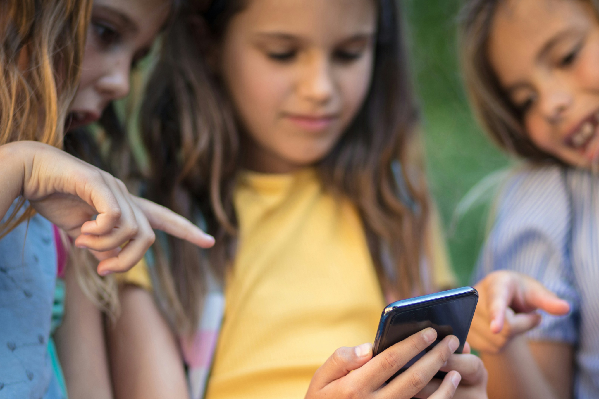 3 Mädchen gucken gemeinsam auf ein Handy