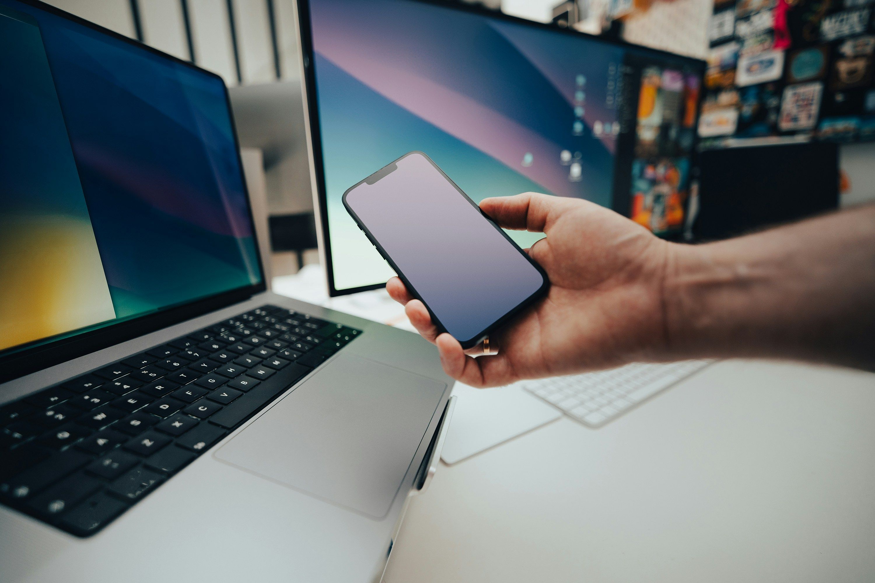 Softwareentwickler zeigt Laptop, PC und Handy mit der gleichen Websoftware