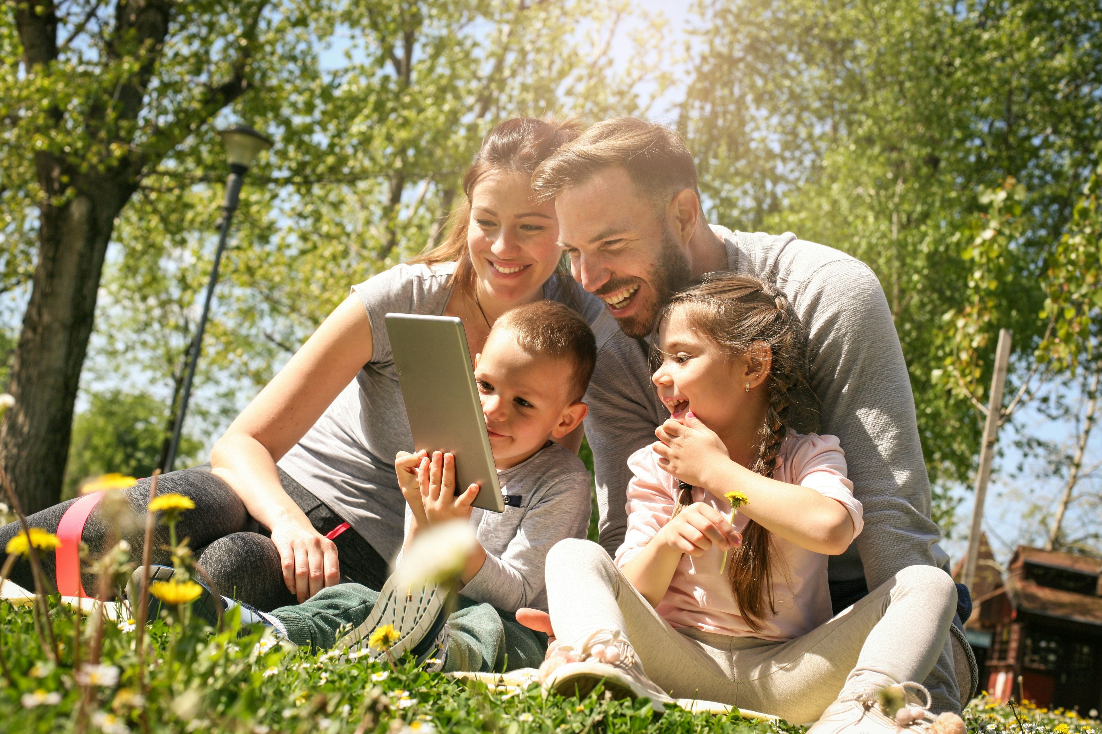 Familie sitzt im Park und gucken zusammen aufm Handy